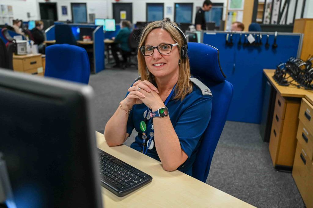 Lisa sitting at her desk in the force control room, smiling at the camera. She has her hands clasped in front of her.