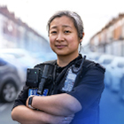 A female police officer standing in a street with her arms crossed