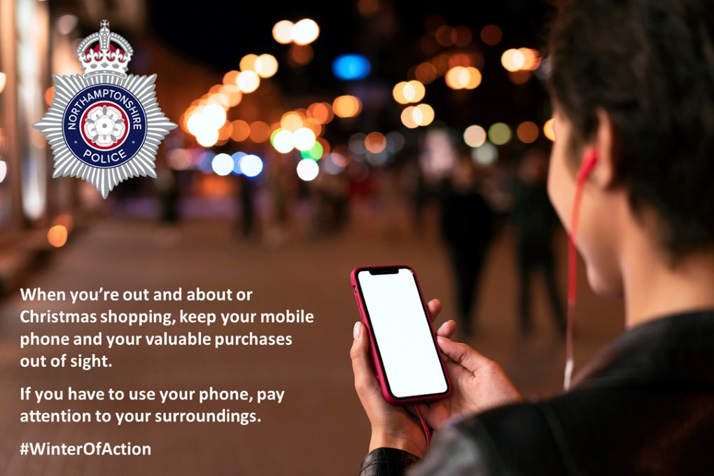 A man walking along the street looking at his mobile phone, with the words 'When you're out and about or Christmas shopping, keep your mobile phone and valuable purchases out of sight. If you have to use your phone, pay attention to your surroundings.’  Image by Freepik